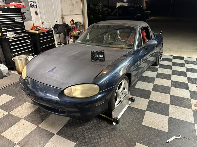 Blue Mazda Miata on turn plates for an alignment